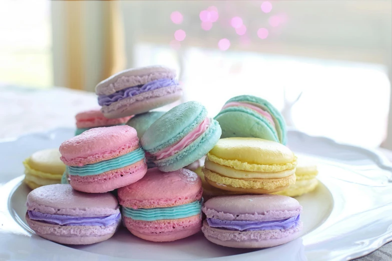 a white plate topped with lots of colorful macarons, a colorized photo, by Alice Mason, pexels, mauve and cyan, 🎀 🧟 🍓 🧚, canva, delicious food