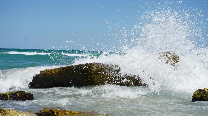 a man riding a wave on top of a surfboard, unsplash, process art, waves crashing at rocks, on a hot australian day, sparkling water, rocky seashore