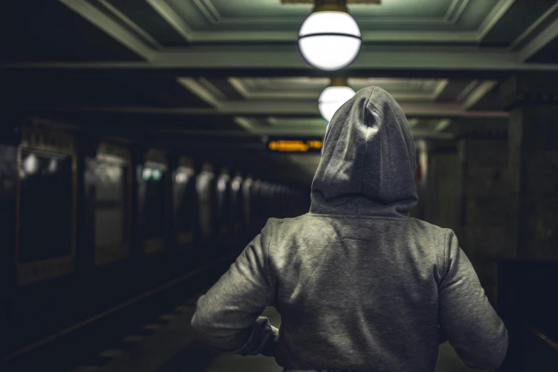 a person wearing a hoodie in a subway station, pexels contest winner, workout, back facing the camera, an intruder, grey clothes