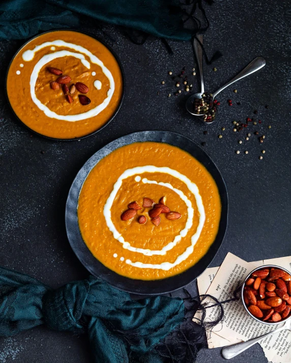 two bowls of soup sitting on top of a table, unsplash contest winner, hurufiyya, on a dark background, pumpkin, high quality product image”, background image