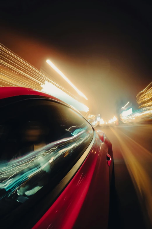 a red car driving down a street at night, pexels contest winner, hyperspeed, up close, inside of a car, warp