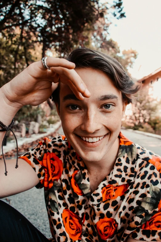a young man sitting on the side of a road, a polaroid photo, inspired by Luca Zontini, trending on pexels, renaissance, wearing a tie-dye shirt, slightly awkward smile, patterned clothing, closeup headshot