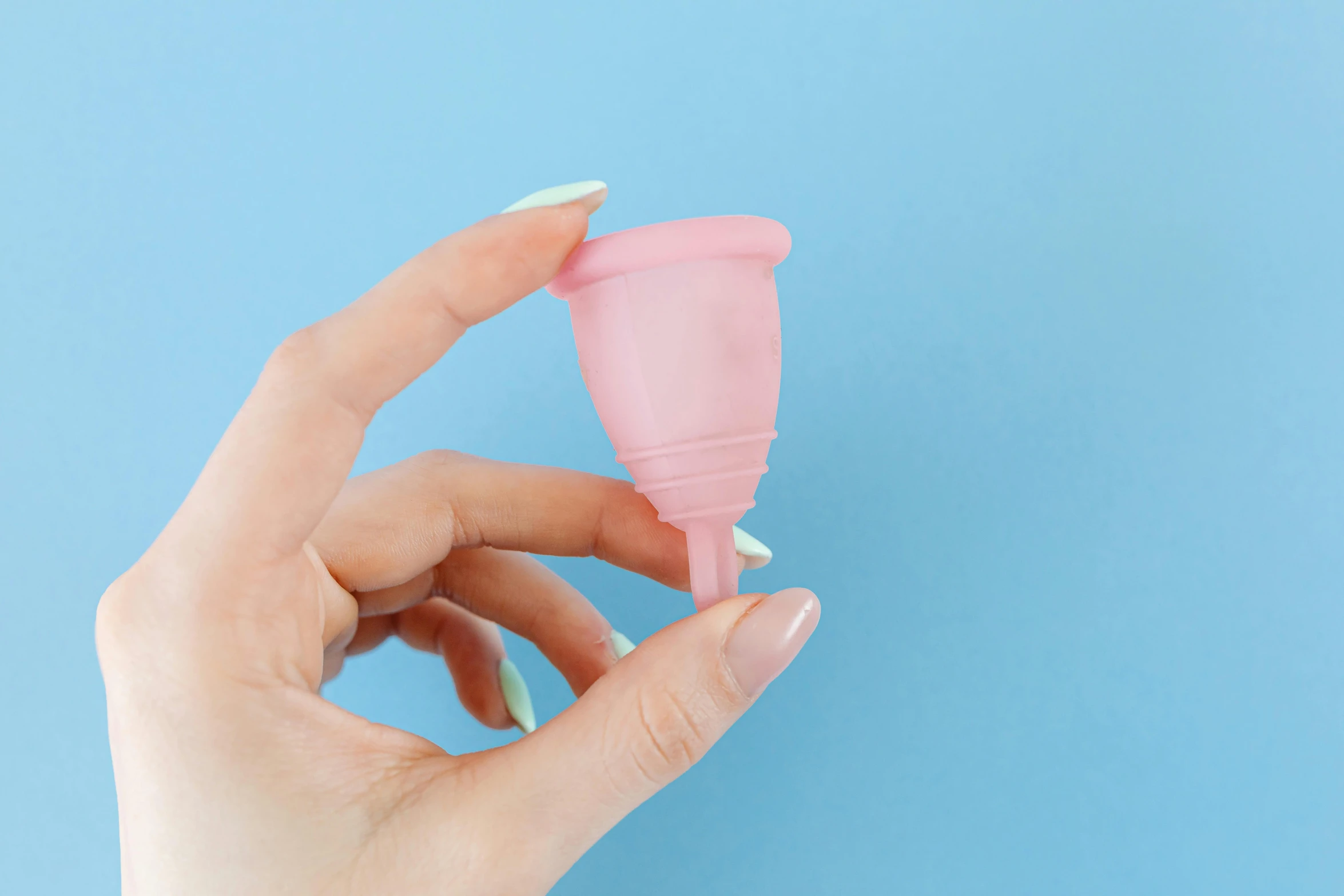 a woman's hand holding a pink dispenser against a blue background, plasticien, d-cup, unicorn horn, highly capsuled, on a pale background