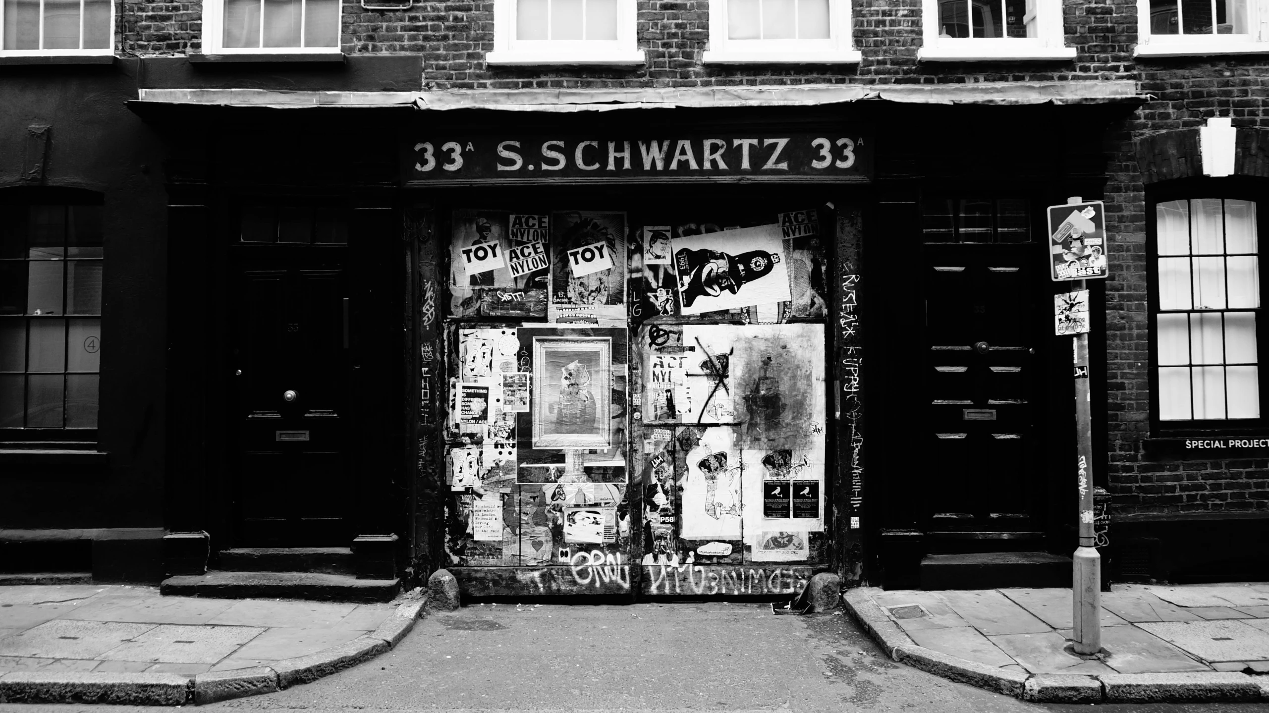 a black and white photo of a store front, an album cover, inspired by Hans Schwarz, sots art, platform 9 3 / 4, there were posters on the wall, herman nitsch, schizophrenic