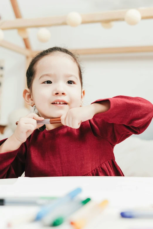 a little girl sitting at a table brushing her teeth, a child's drawing, pexels contest winner, wearing a red cheongsam, default pose neutral expression, holding a crowbar, gif