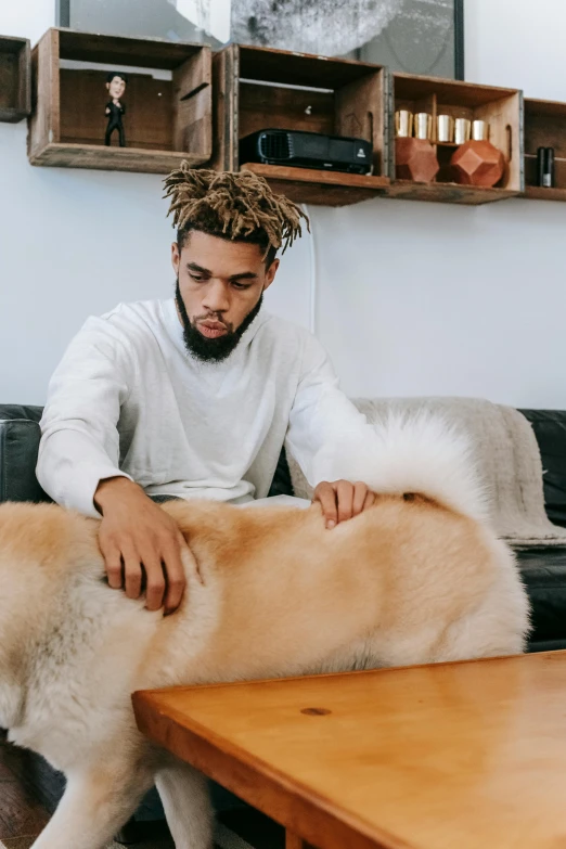 a man sitting on a couch petting a dog, by Frank Mason, trending on pexels, visual art, cornrows, xxxtentacion, thick fluffy tail, sitting on a table