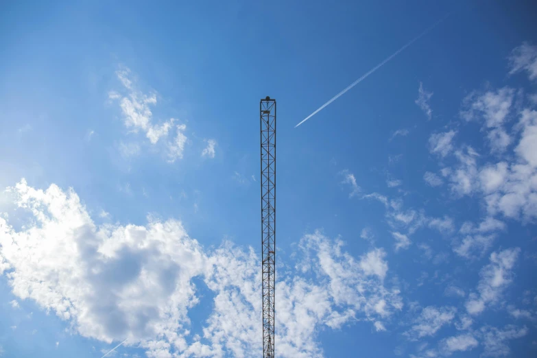 a tall tower sitting on top of a lush green field, by Jan Tengnagel, unsplash, postminimalism, antenna, blue sky, industrial photography, ignant