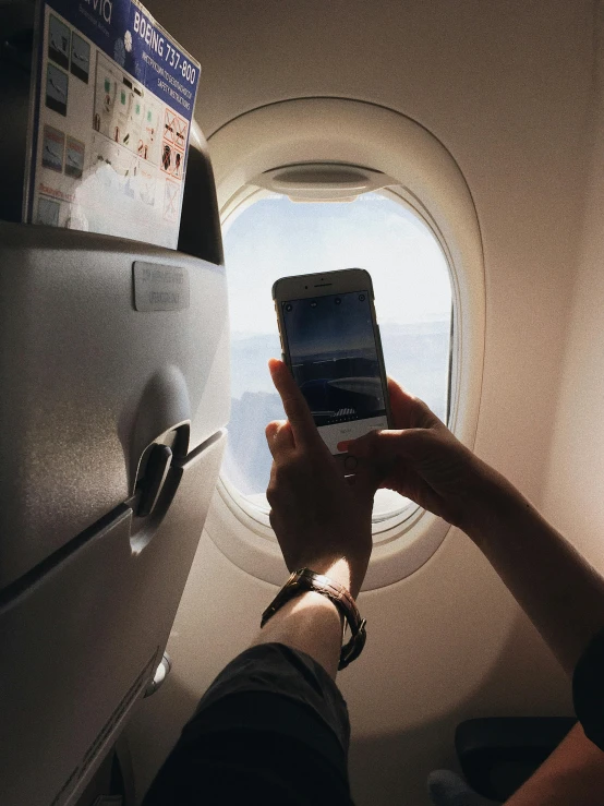 a person holding a cell phone in front of an airplane window, profile image, flatlay, multiple stories, album photo