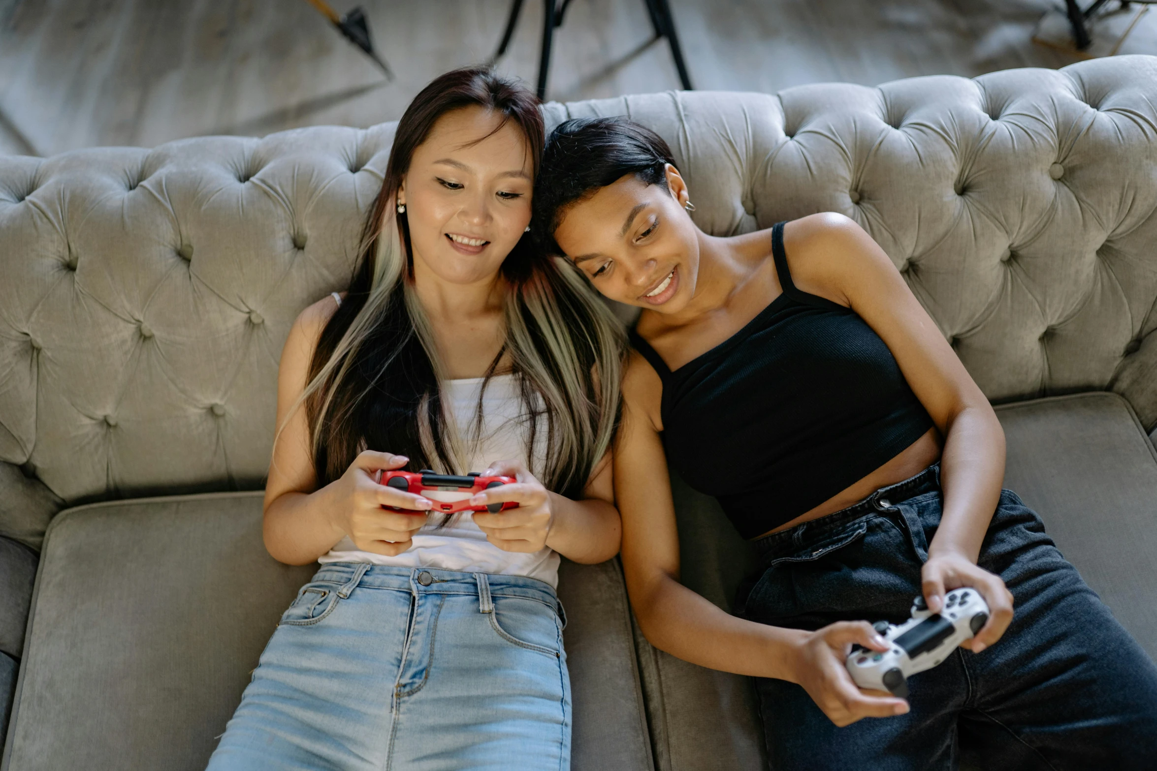 a couple of women sitting on top of a couch, trending on pexels, mobile game style, half asian, black, teenagers