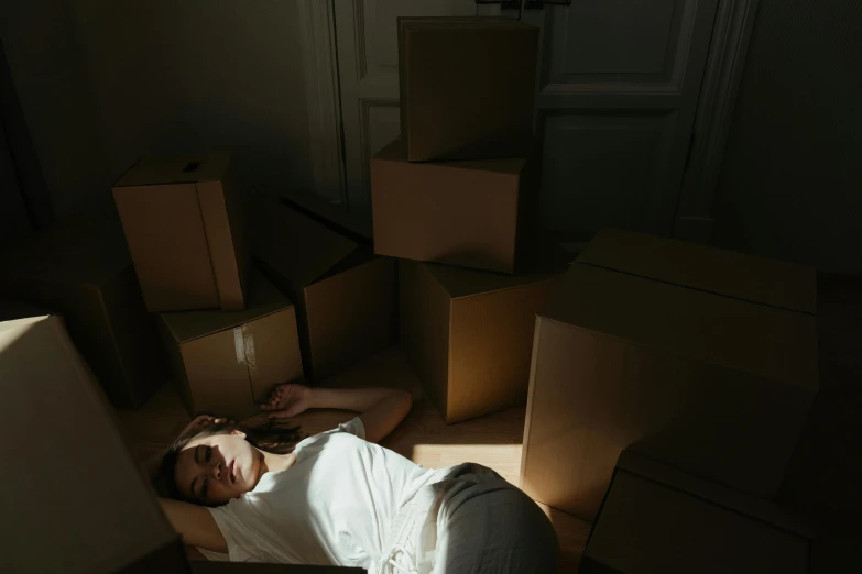 a woman laying on the floor surrounded by boxes, inspired by Elsa Bleda, pexels contest winner, light and space, standing in a dimly lit room, sleep paralysis, gif, blinding sun