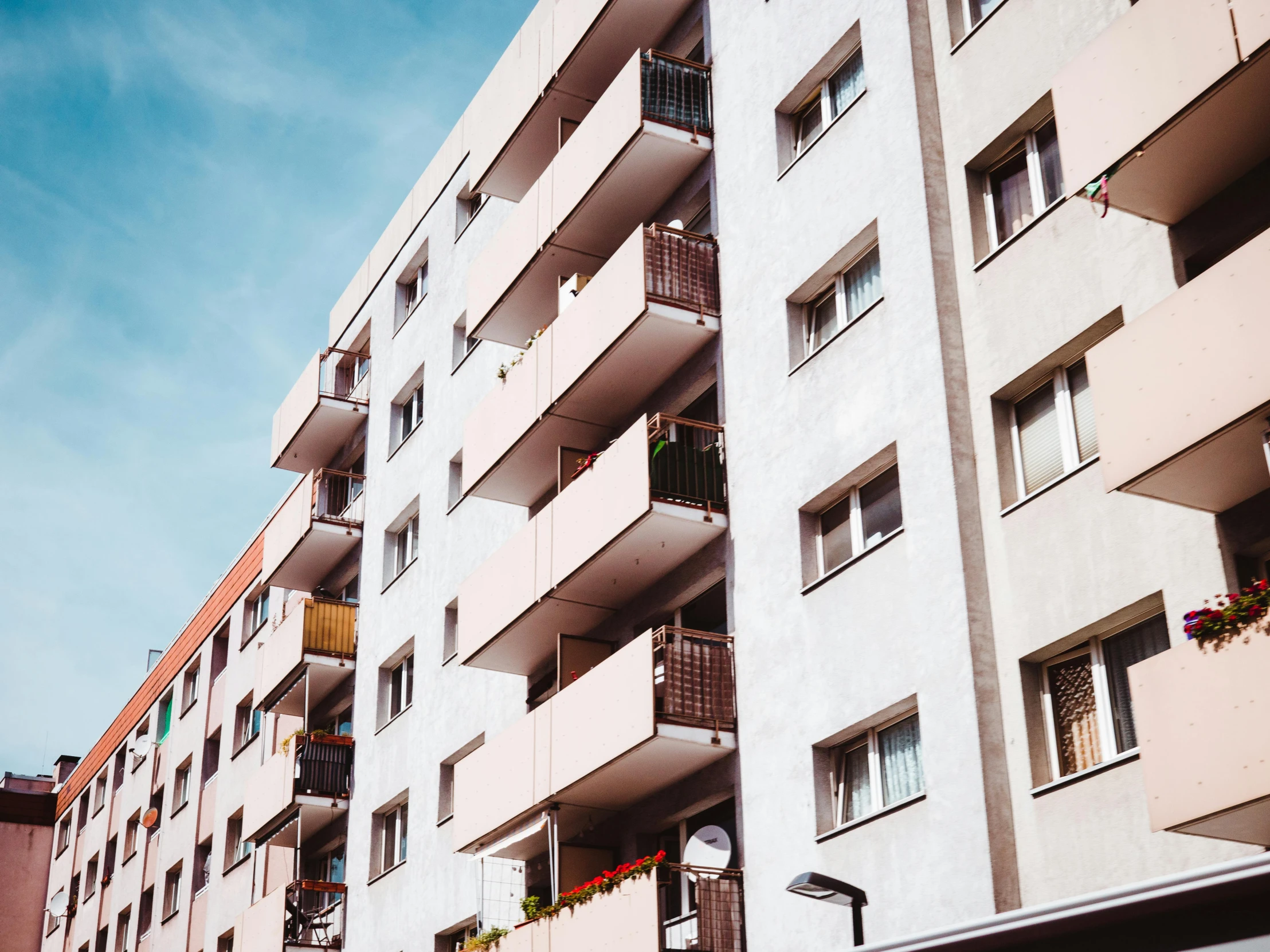 an apartment building with balconies on the balconies, a photo, pexels contest winner, bauhaus, fan favorite, white pale concrete city, youtube thumbnail, other smaller buildings