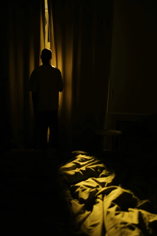 a person standing next to a bed in a dark room, happening, harsh sunlight, ap news photograph, may 1 0, silhouette :7