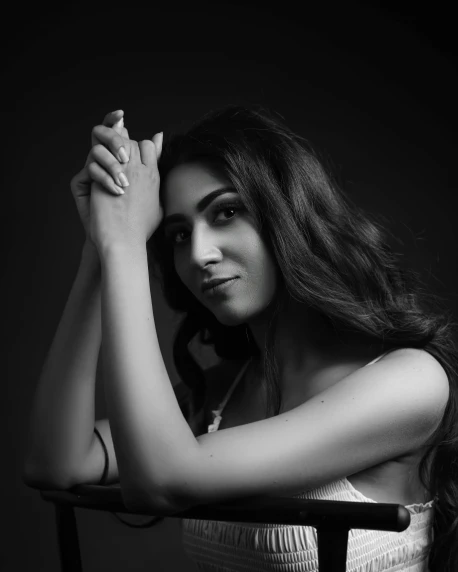 a woman sitting in a chair with her hand on her head, a black and white photo, inspired by Yousuf Karsh, pexels contest winner, maya ali as d&d mage, candid!! dark background, mia khalifa, portait photo profile picture