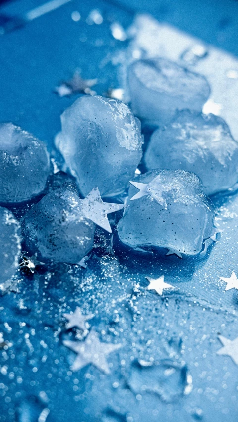 a pile of ice sitting on top of a blue surface, inspired by Vija Celmins, trending on pexels, twinkling stars, molecular gastronomy, thumbnail, hi-res