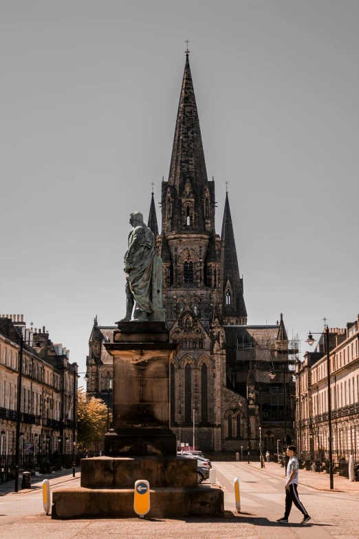 a man walking down a street past tall buildings, a statue, by Andrew Robertson, pexels contest winner, art nouveau, tall stone spires, highlands, lead - covered spire, slate