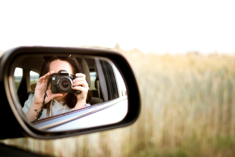 a woman taking a picture of herself in a rear view mirror, a picture, inspired by Vivian Maier, unsplash, canvas, ultrawide lens”, outdoor photo, avatar image