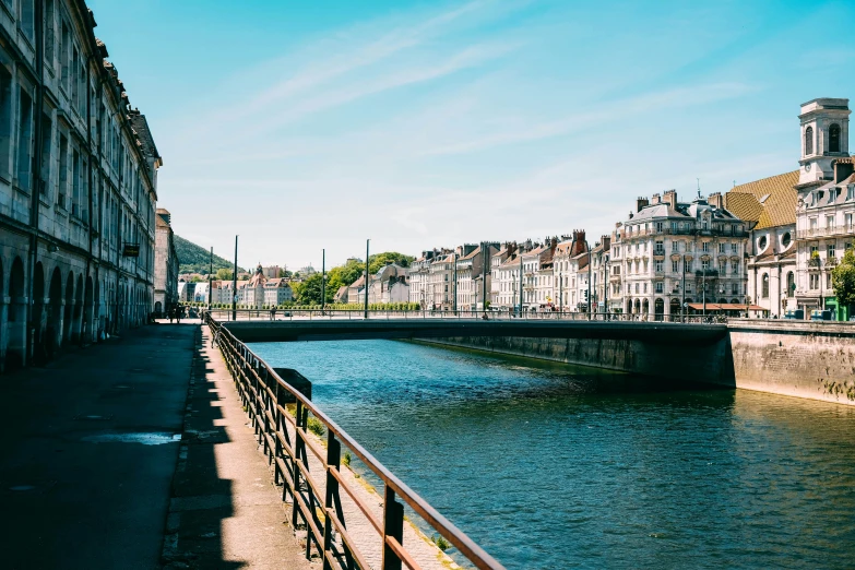 a river running through a city next to tall buildings, by Raphaël Collin, pexels contest winner, liege, a photo of a lake on a sunny day, city bay bridge aqueduct, square