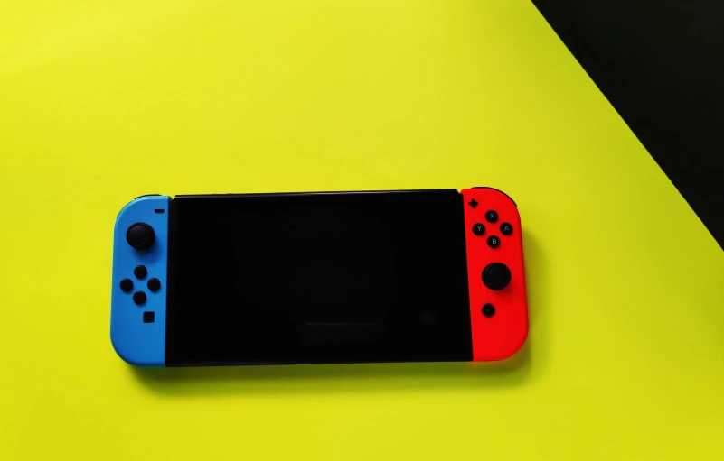a nintendo switch lite sitting on top of a yellow table, pexels, red and blue black light, portrait n - 9, plain background, colorful picture