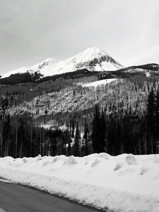 a black and white photo of a snow covered mountain, on the side of the road, aspen grove in the background, listing image, volcanoes