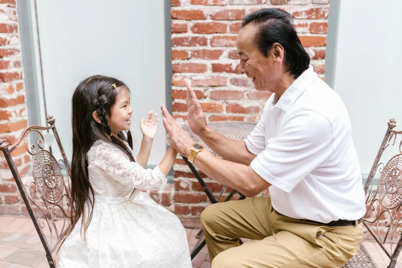 a man sitting next to a little girl on a chair, pexels contest winner, waving hands, asian descent, profile image, white sleeves