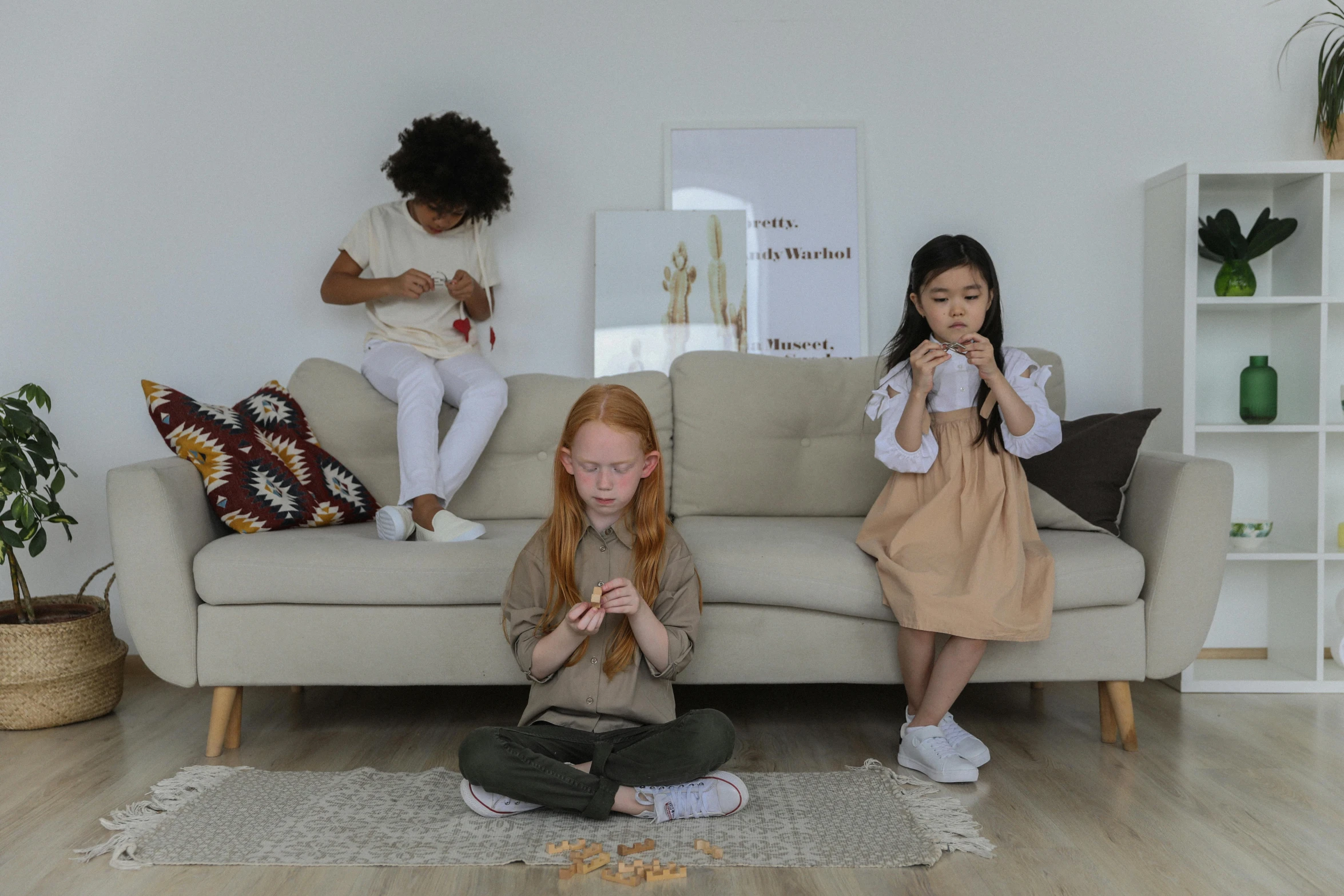 a couple of girls sitting on top of a couch, pexels contest winner, kids playing, triad of muses, brown clothes, as 3 figures