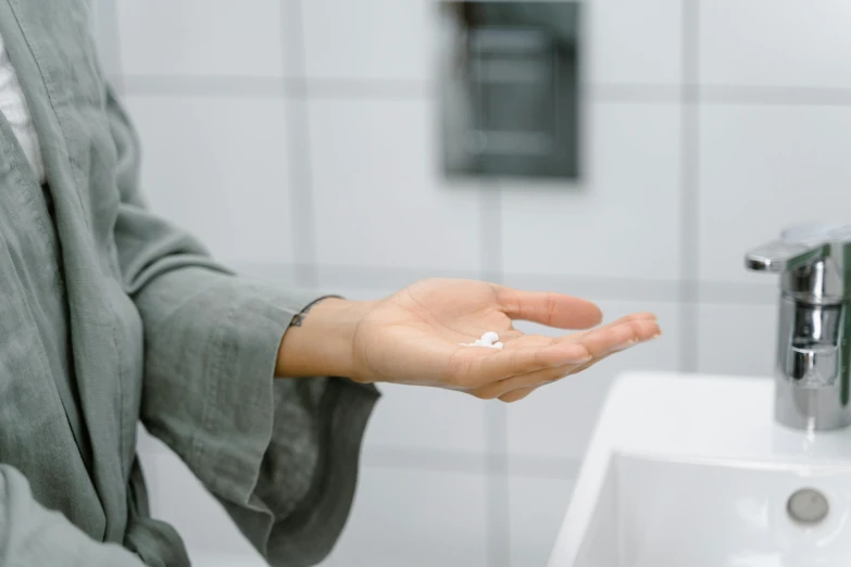 a woman using a hand sanitizer to clean her hands, by Emma Andijewska, pexels, square, commercial washroom hand dryer, offering the viewer a pill, [ cinematic