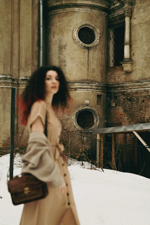 a woman walking across a snow covered street, an album cover, pexels contest winner, renaissance, brown curly hair, standing in abandoned building, russian style, muted colors. ue 5