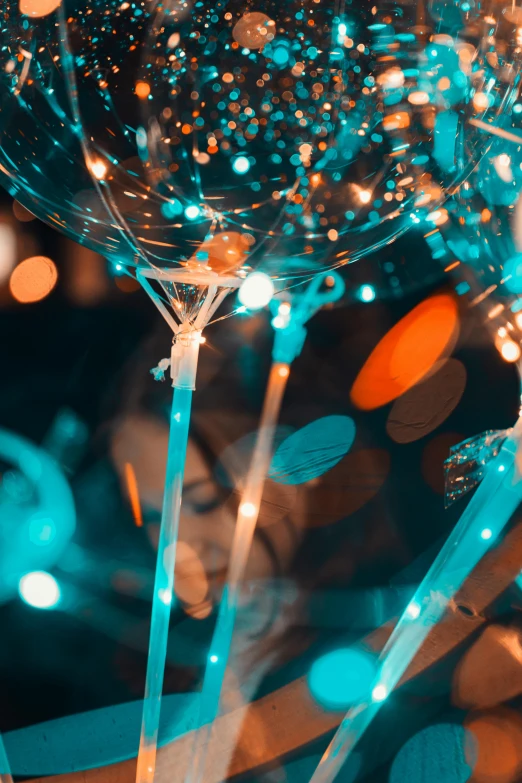 a bunch of balloons sitting on top of a table, inspired by Bruce Munro, pexels contest winner, glassware, teal lights, dynamic closeup, sparks