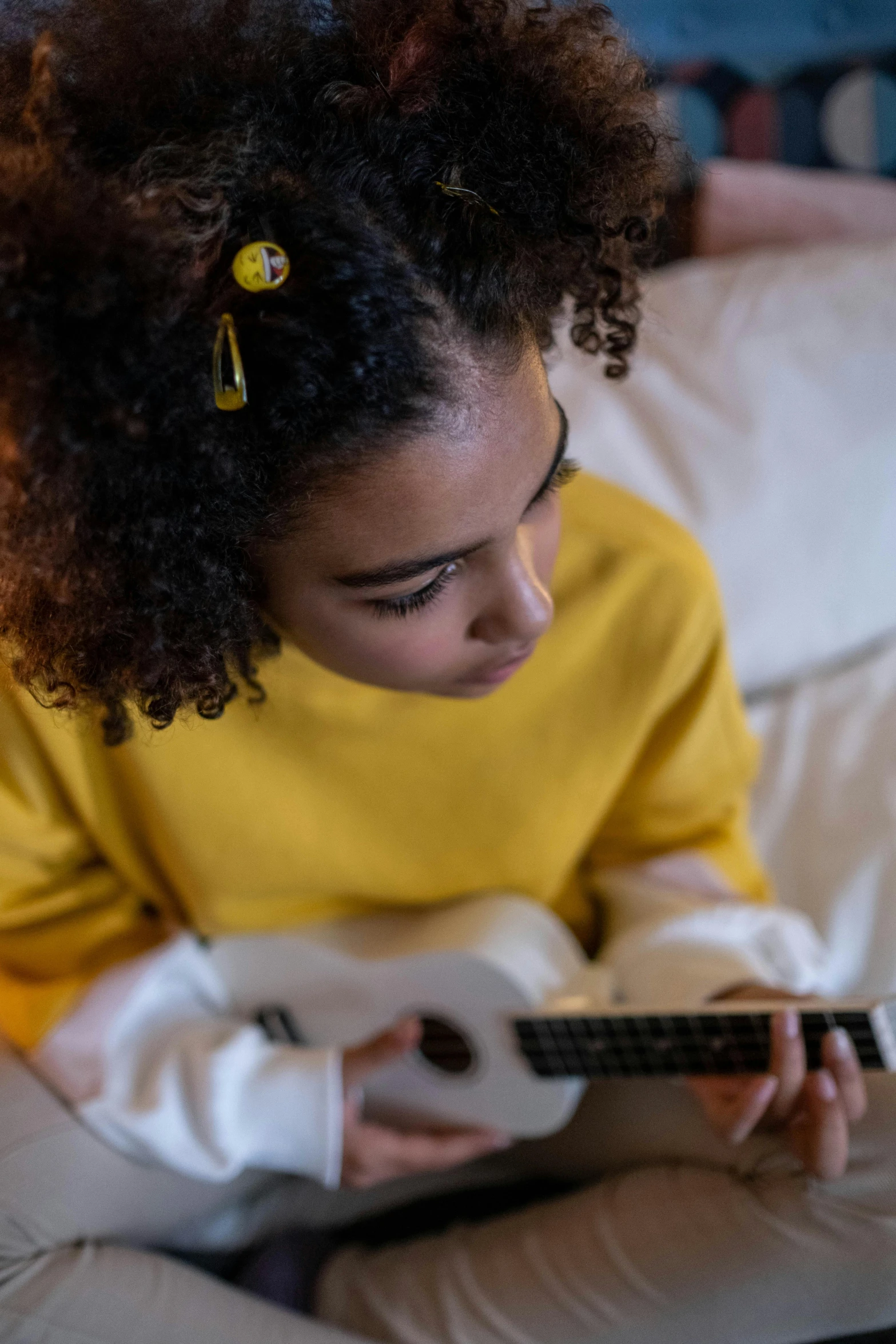 a young girl sitting on a couch playing a guitar, trending on pexels, wavy hair yellow theme, someone in home sits in bed, schools, thumbnail