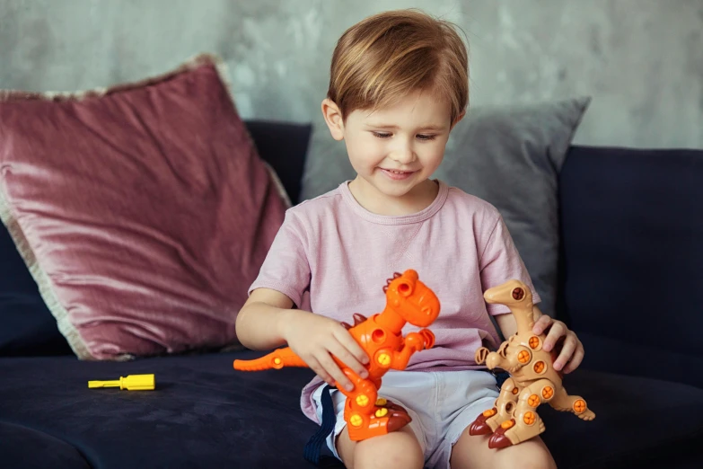 a little boy that is sitting on a couch, inspired by Abidin Dino, pexels contest winner, articulated joints, the woman holds more toys, vibrant orange, activity play centre