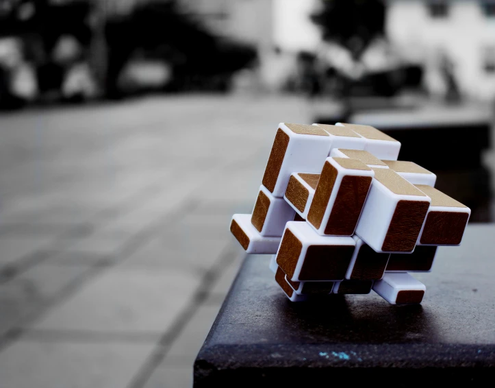 a piece of paper sitting on top of a table, an abstract sculpture, inspired by Ernő Rubik, unsplash, cubo-futurism, minecraft in real life, tiltshift, made of wood!!!!!, cross composition