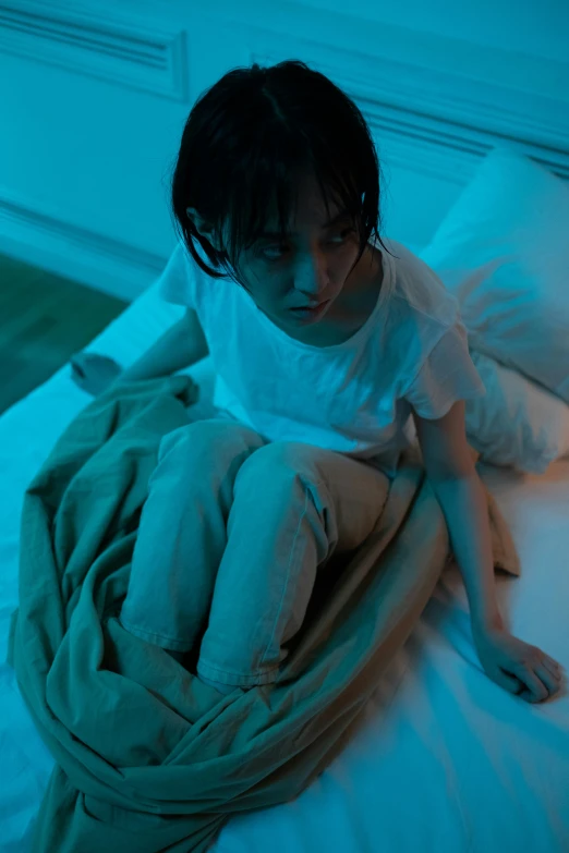 a little girl sitting on top of a bed under a blanket, inspired by Gottfried Helnwein, pexels contest winner, conceptual art, ambient teal light, looking threatening, young asian girl, cyan