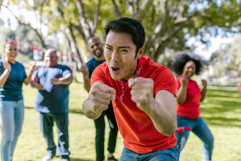 a group of people standing on top of a lush green field, inspired by Liao Chi-chun, pexels contest winner, happening, boxing stance, red shirt, at a park, line dancing at a party
