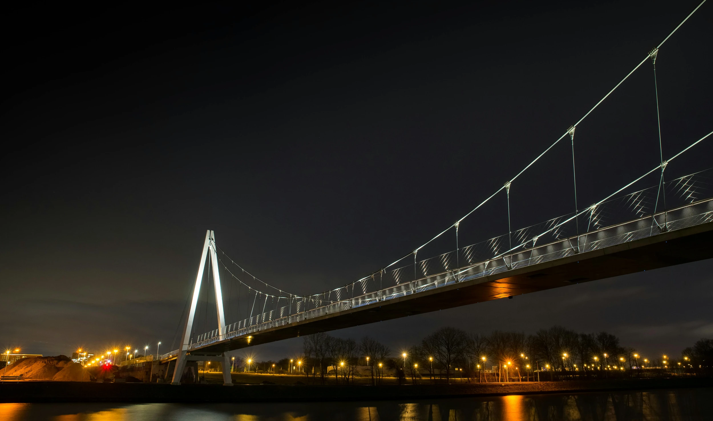 a bridge over a body of water at night, by Jacob Toorenvliet, pexels contest winner, helmond, metallic bridge, high detail photo, fan favorite