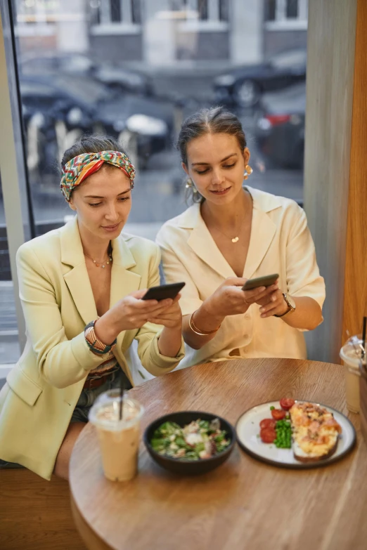 two women sitting at a table looking at a cell phone, by Emma Andijewska, trending on pexels, renaissance, trendy food, well - dressed, with long, ukrainian