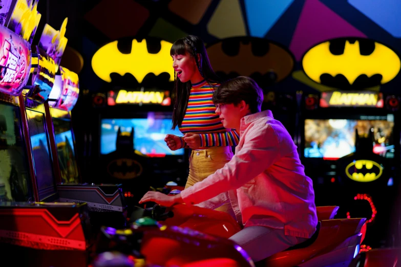 a man and a woman playing a video game, pexels, pop art, film still of batman, a busy arcade, rides, batgirl