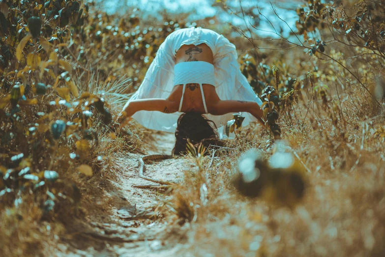 a woman doing a handstand in a field, pexels contest winner, wearing white silk hood, cardboard, avatar image, covered in plants