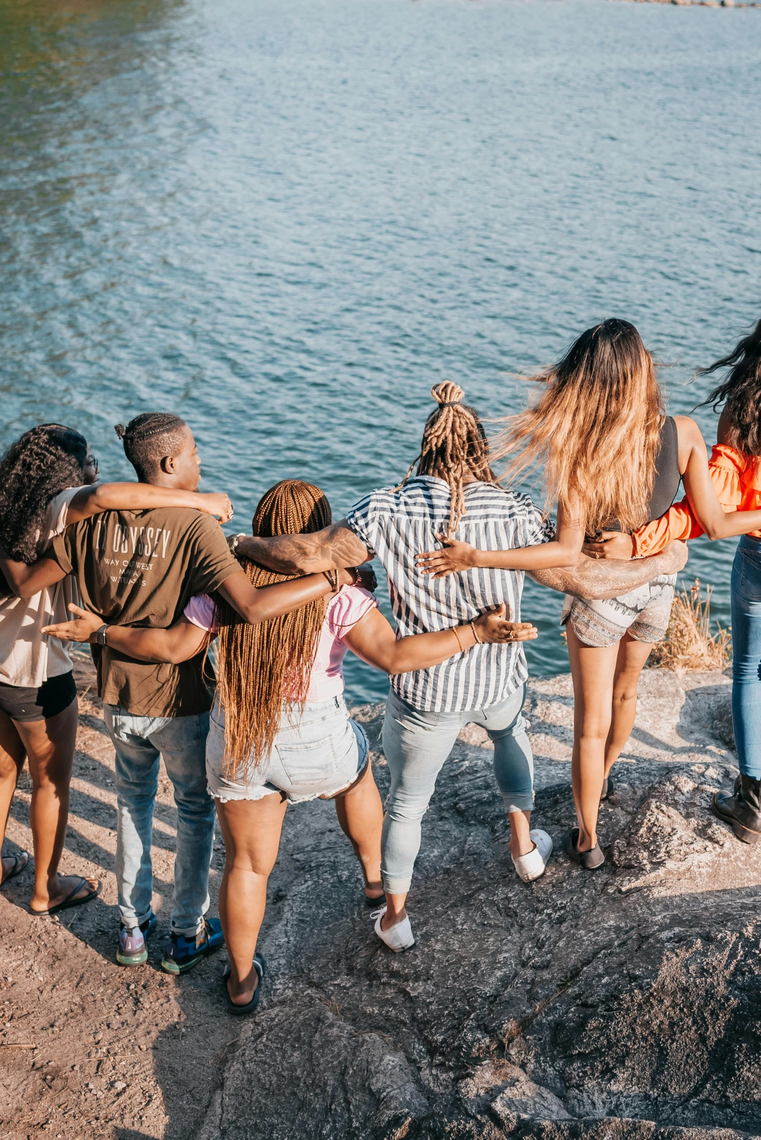 a group of people standing next to a body of water, trending on pexels, happening, hugging her knees, diverse colors, college girls, flatlay