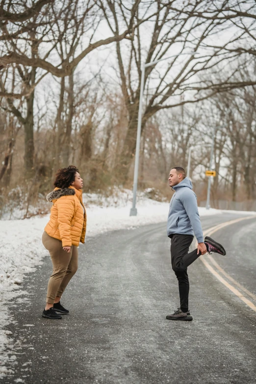 a couple of people standing on the side of a road, by Washington Allston, pexels contest winner, winter vibrancy, playful pose, thicc, run