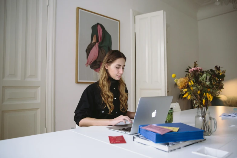 a woman sitting at a table using a laptop computer, inspired by Louisa Matthíasdóttir, pexels contest winner, arbeitsrat für kunst, low quality photo, profile image, casually dressed, centered shot