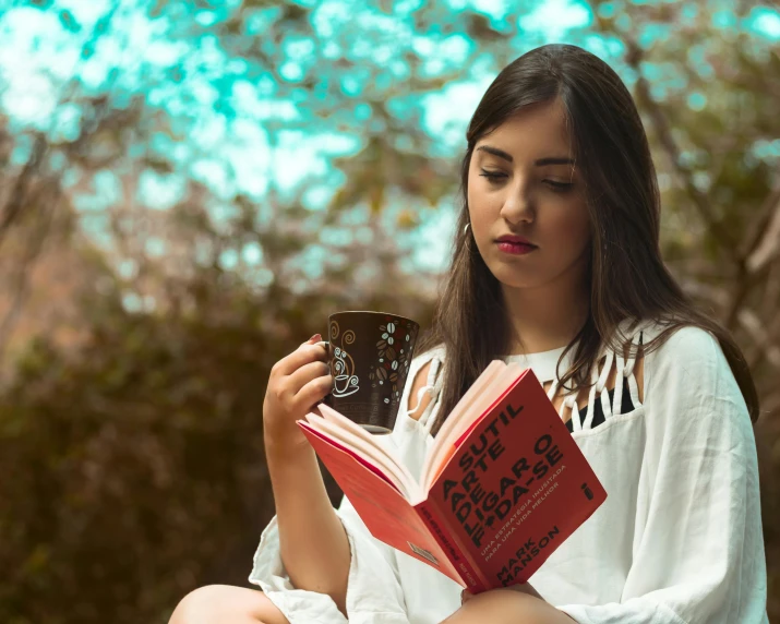 a woman sitting on a bench reading a book, pexels contest winner, with a white mug, indian girl with brown skin, background image, girl with dark brown hair