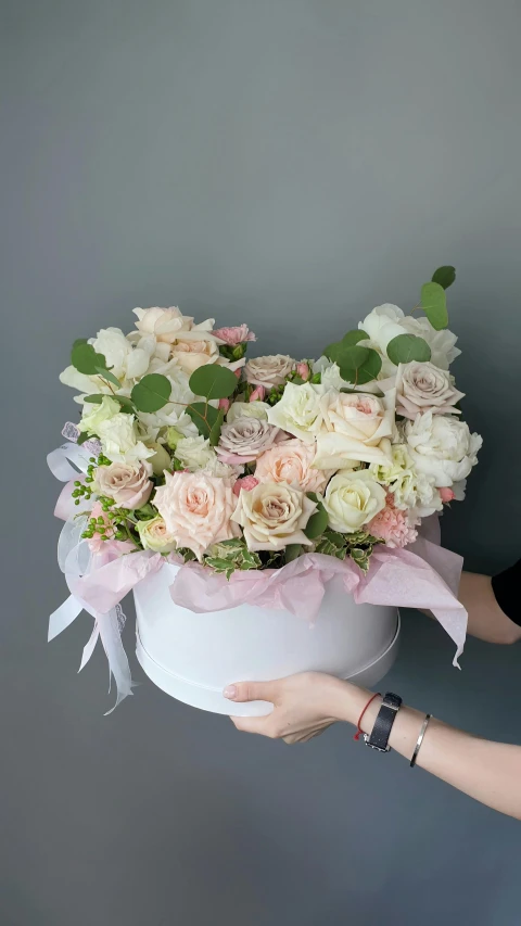 a woman holding a white bowl filled with pink and white flowers, white box, crown of mechanical peach roses, pale greens and whites, medium close shot