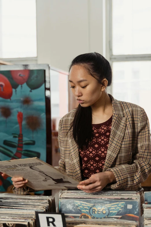 a woman looking at records on a table, a portrait, inspired by Fei Danxu, academic art, in a studio, asian descent, cardboard, trending on