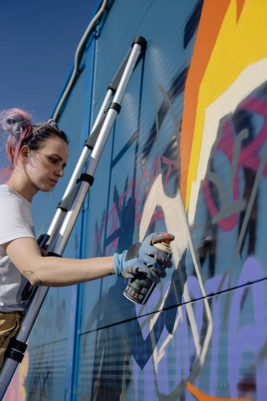 a woman is painting a mural on the side of a building, trending on pexels, graffiti, lgbt art, artist wearing overalls, profile image, grimes