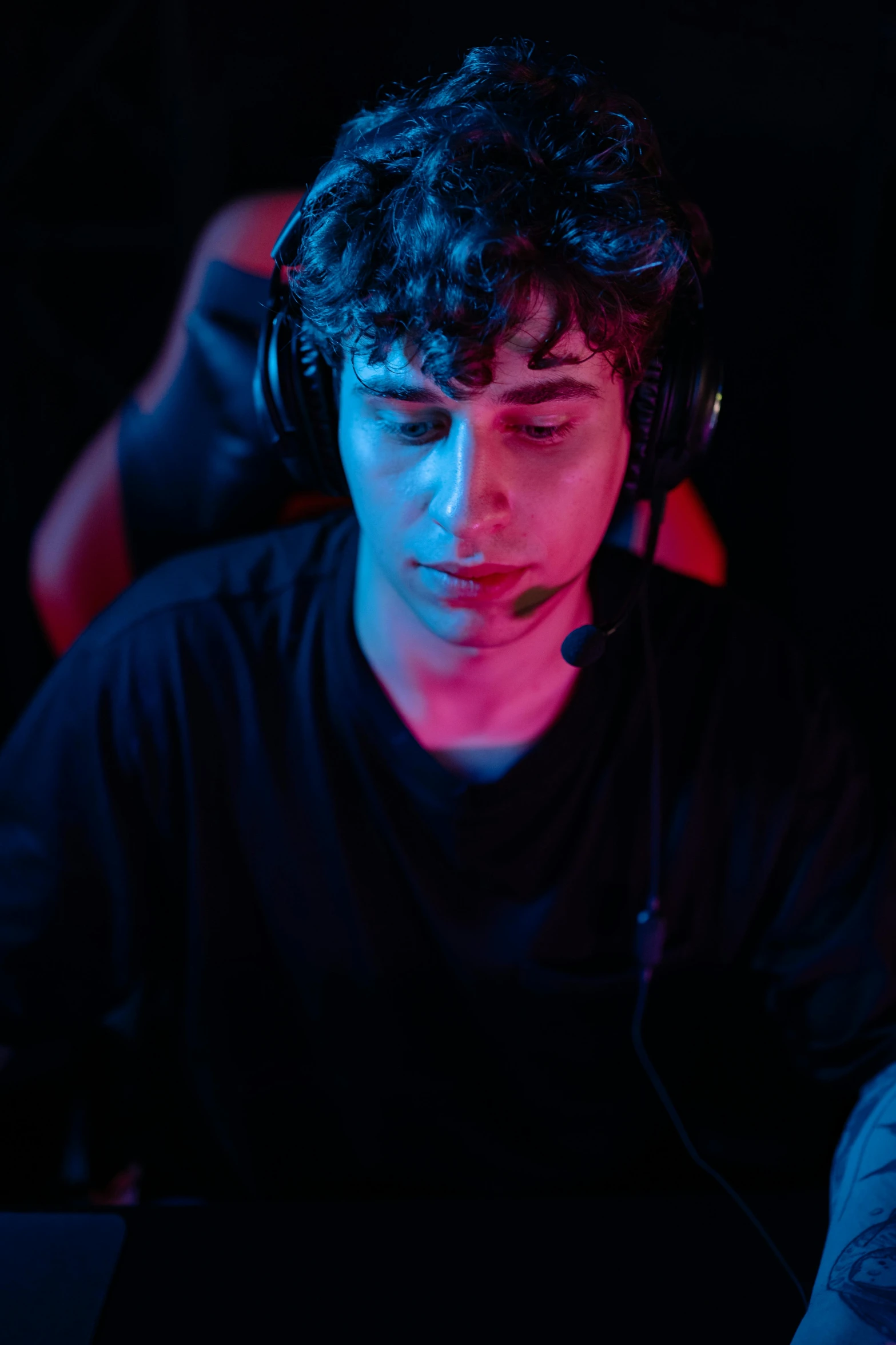 a man sitting in front of a laptop wearing headphones, a character portrait, tournament, with a black background, curls on top, diego fernandez