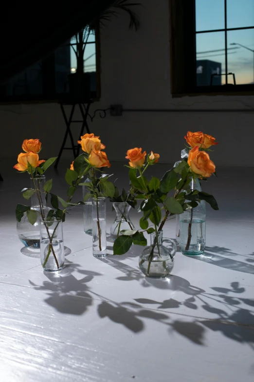 a number of vases with flowers in them on a table, inspired by Elsa Bleda, unsplash, photorealism, crown of mechanical peach roses, sunset raked lighting, glass studio, in an urban setting