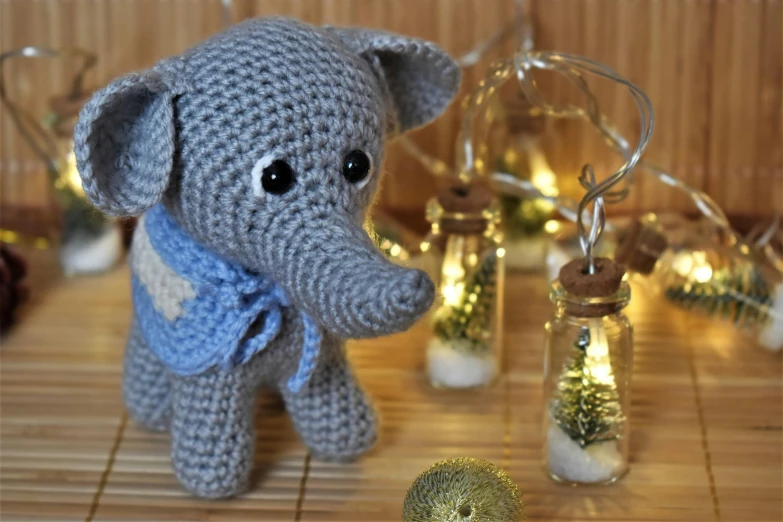a close up of a stuffed animal on a table, by Emma Andijewska, pixabay, string lights, elephants, crochet, 240p