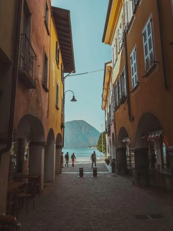 a couple of buildings that are next to each other, by Julia Pishtar, pexels contest winner, renaissance, mountains and lakes, walking down a street, bizzaro, summer street near a beach