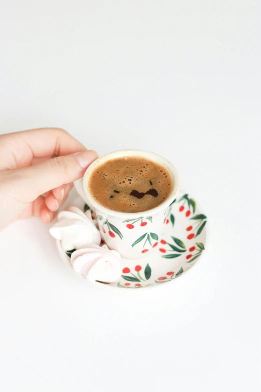 a person is holding a cup of coffee, by Lucia Peka, arabesque, some chocolate sauce, cheeryblossom, with a white background, patterned
