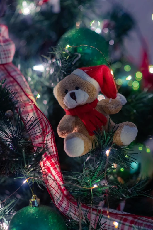 a teddy bear sitting on top of a christmas tree, zoomed in, fully decorated, fan favorite, lit up